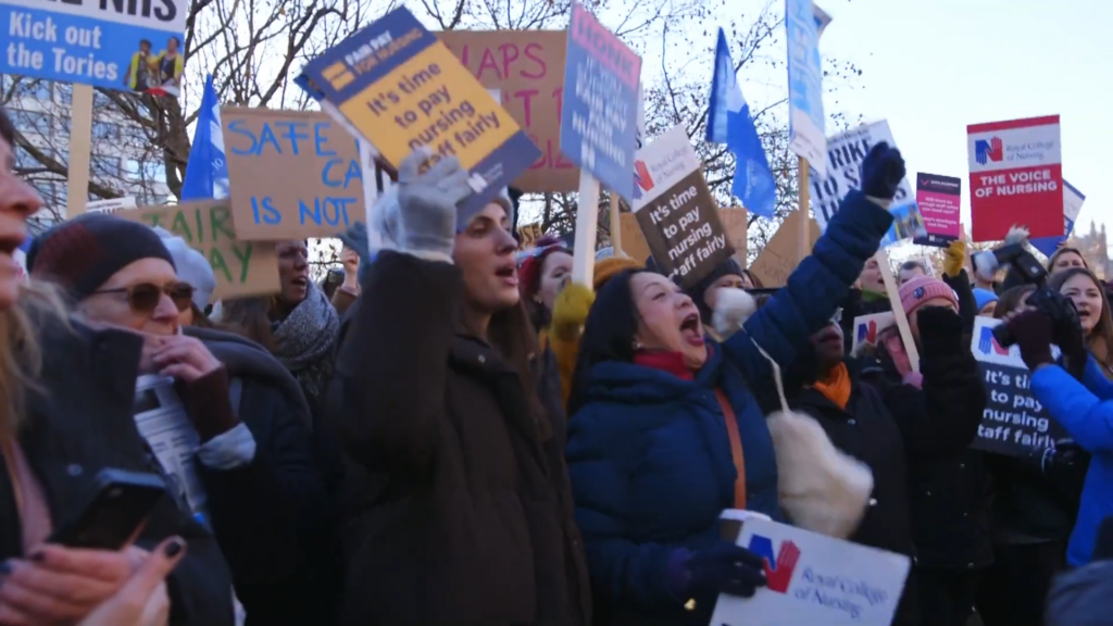 NHS doctors and nurses picketing outside a hospital with signs demanding fair pay