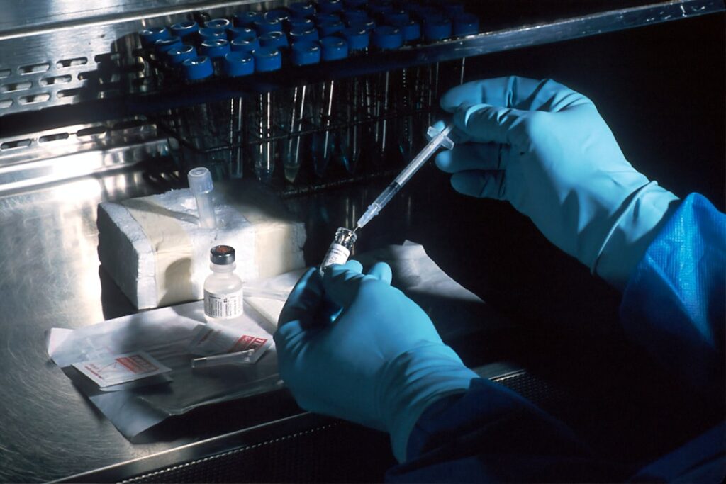 A scientist in a white lab coat examines a vial of CRISPR gene therapy at a manufacturing facility in Framingham, Massachusetts.