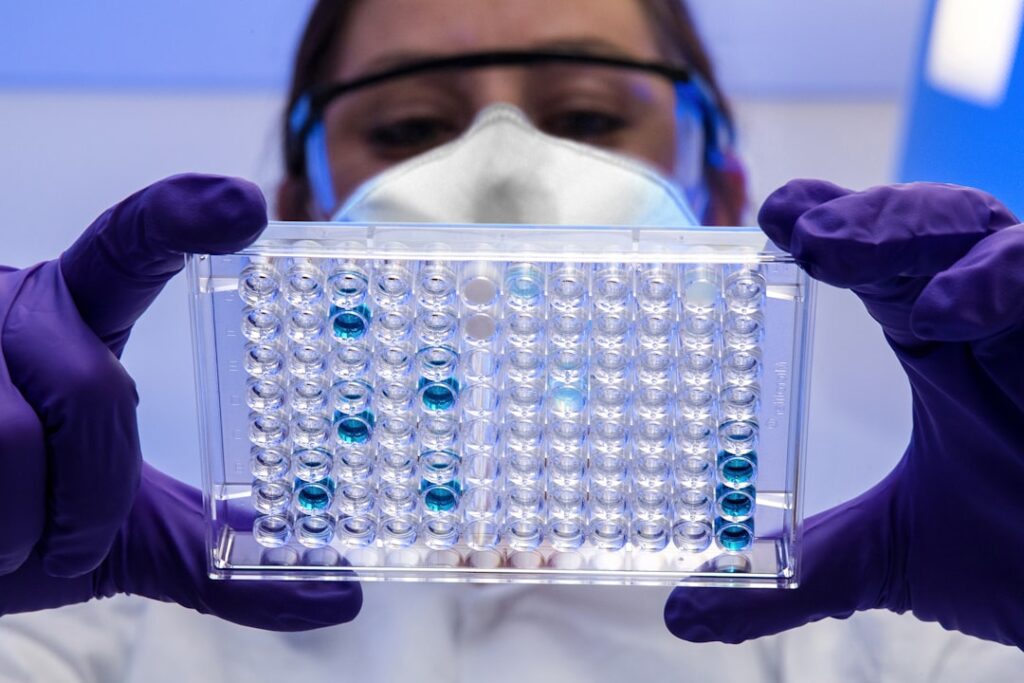 A medical researcher holds a vial of zolbetuximab labeled Vyloy in a laboratory setting.